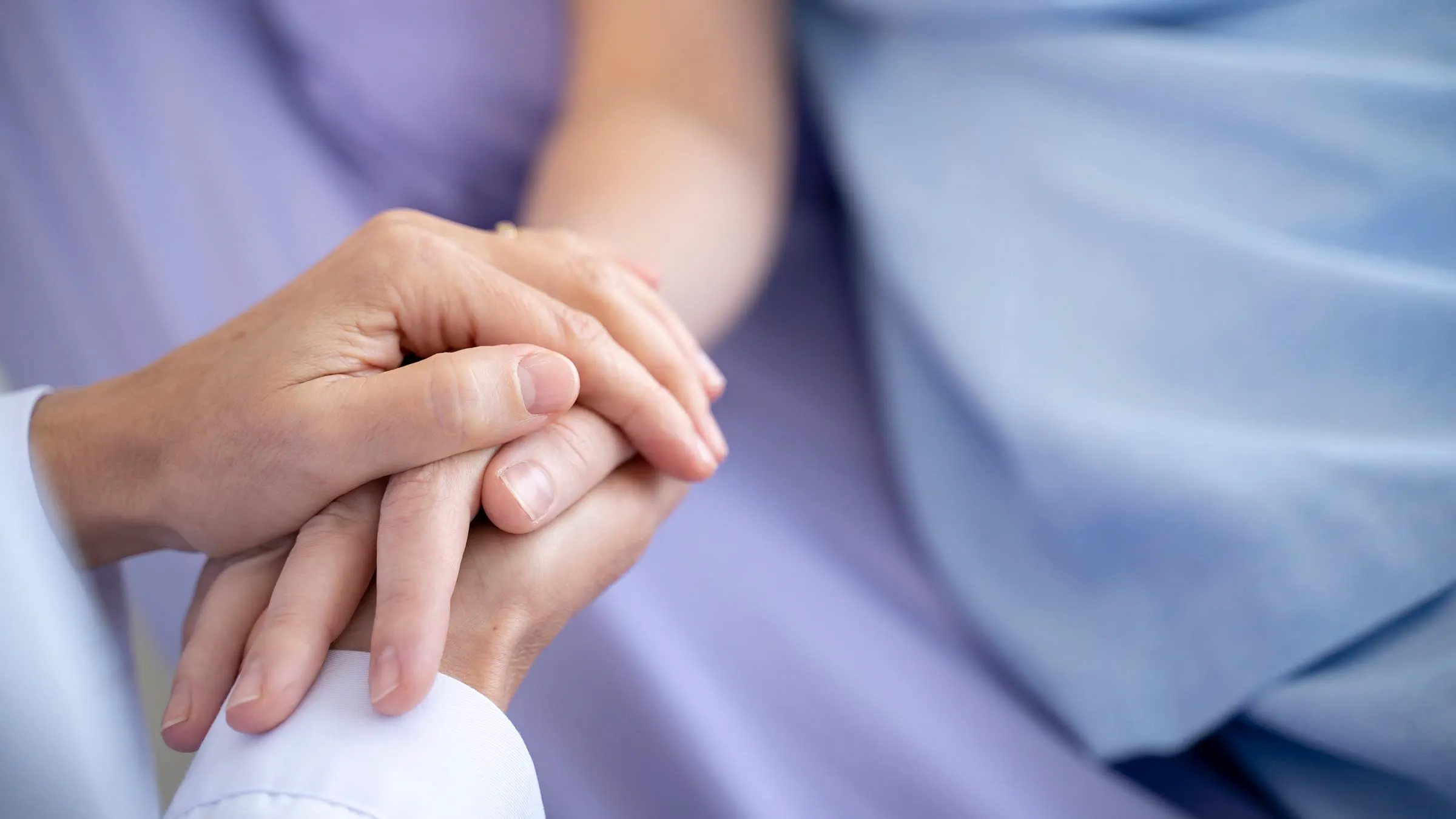 Caregiver holding patient's hand during palliative care visit