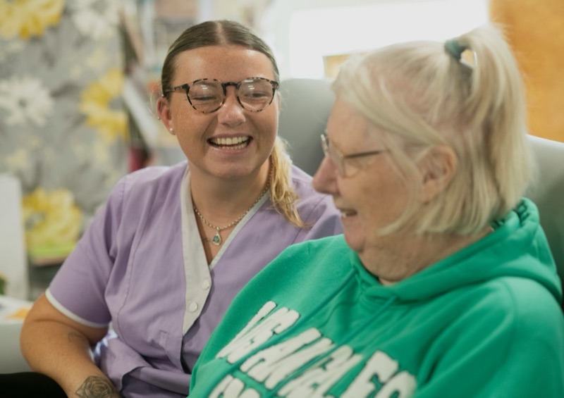 Hospice caregiver sharing a light moment with an elderly patient